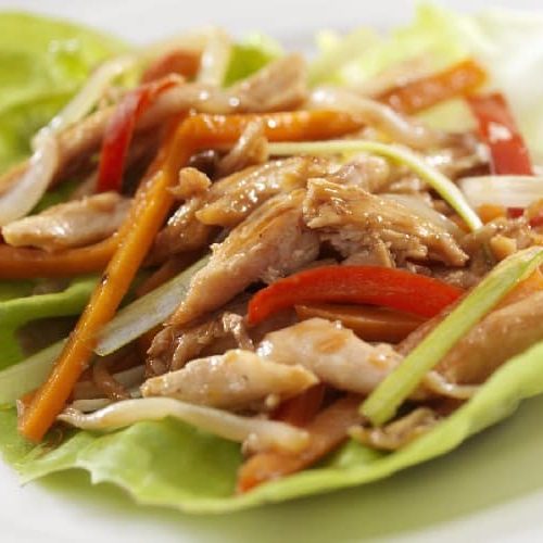 A Wrap Of Cabbage, Chicken, And Assorted Vegetables Sits On A White Plate.
