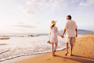 Happy Romantic Middle Aged Couple Enjoying Beautiful Sunset Walk on the Beach. Travel Vacation Retirement Lifestyle Concept