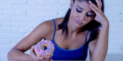 Woman holding donut and making a sad/ashamed expression