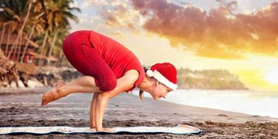 woman doing yoga on the beach at sunrise to show healthy holidays